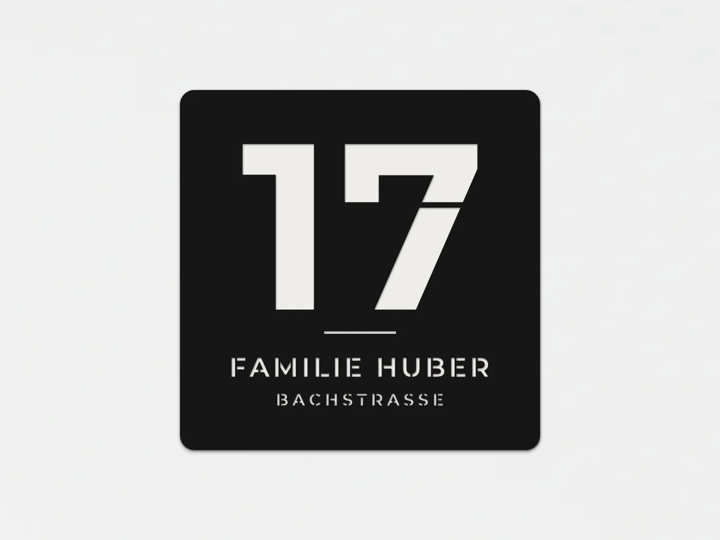 Schwarzes quadratisches Schild mit grosser Hausnummer 17, darunter Familie Huber und Bachstrasse