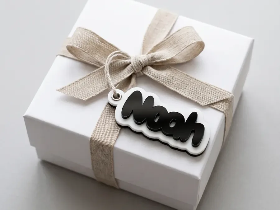 Geschenkanhänger Noah aus schwarzem Acryl mit weissem Rand an einer weissen Geschenkschachtel mit Leinenschleife