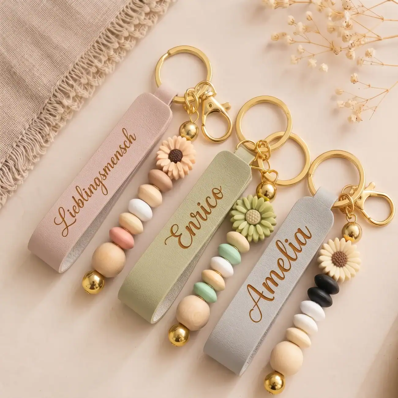 Drei Lederanhänger in Rosa, Olive grün und Grau mit gravierten Namen und Perlen